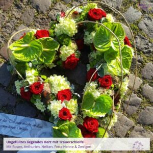 Trauergesteck Herz - Blumenladen Olbernhau Blütenküche - Foto eines liegenden, ungefüllten Herz-Trauergestecks mit Anthurien und Rosen, Draufsicht, fotografiert auf Pflastersteinen
